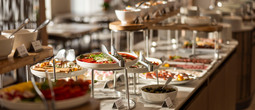 Elegancki bufet hotelowy z sałatkami, wędlinami i oliwkami na wielopoziomowych półkach, ciepłe oświetlenie