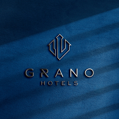 Metaliczne logo GRANO HOTELS z geometryczną ikoną na teksturowanym granatowym tle, elegancka identyfikacja hotelu