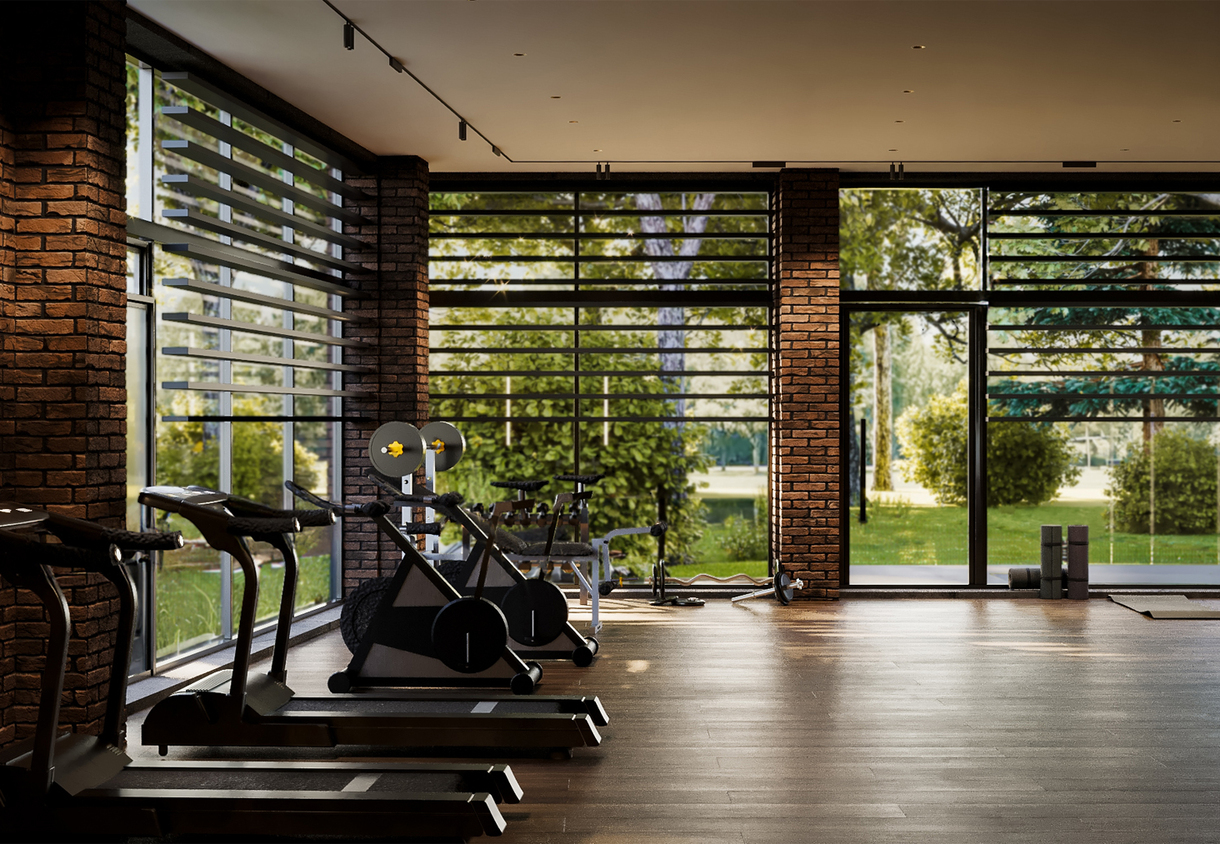 Bright hotel fitness center with treadmills, stationary bikes, free weights, yoga mats and floor-to-ceiling windows.