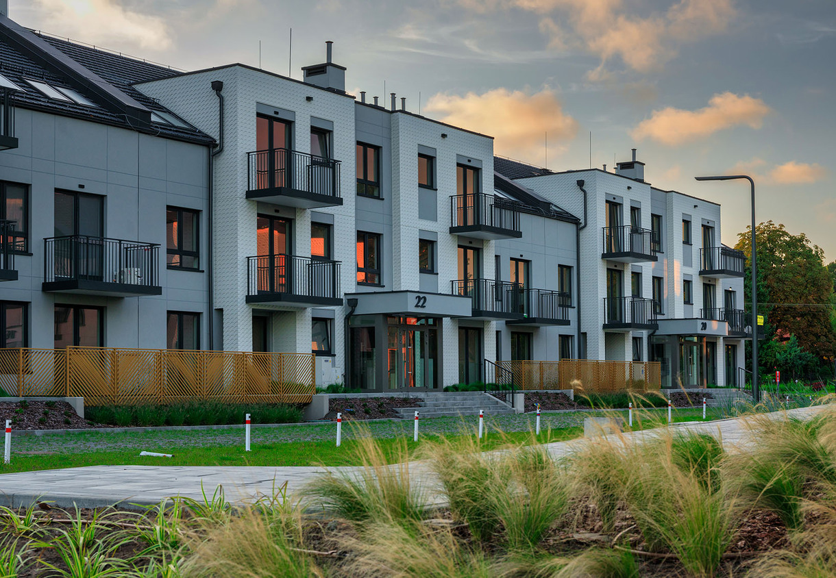 Contemporary three-story aparthotel with private balconies, landscaped grounds and warm evening light reflecting in windows.