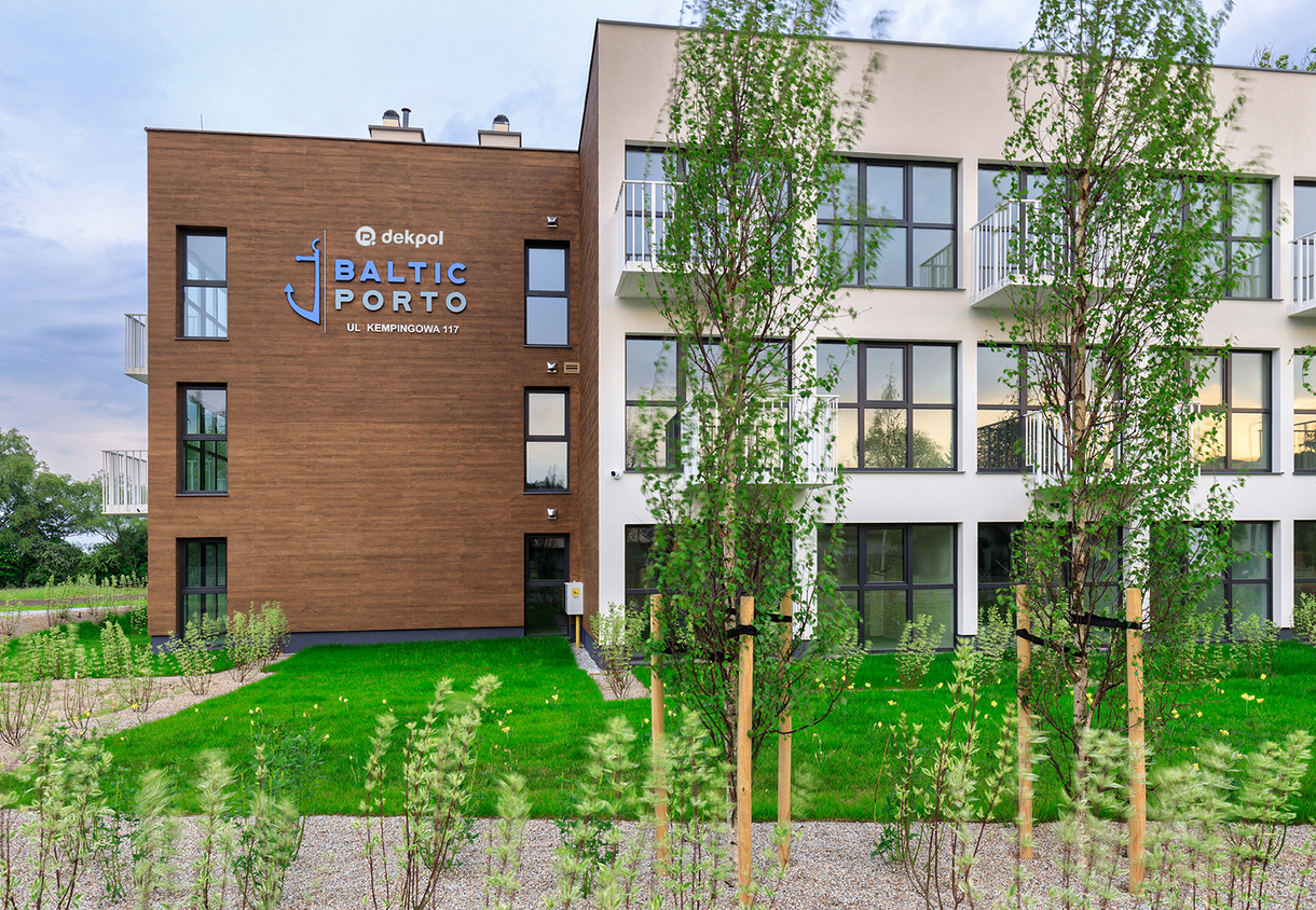 Modern Baltic Porto aparthotel façade with wood-panel section, balconies, lawn and young trees