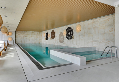 Indoor spa with lap pool and plunge pool, wooden slatted ceiling, wicker pendant lights and cushioned loungers.