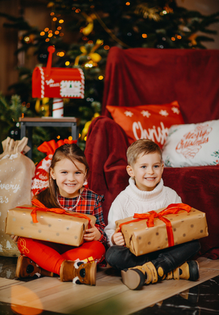 Lächelnde Kinder halten verpackte Weihnachtsgeschenke vor Weihnachtsdekoration im Green Mountain in Karpacz.