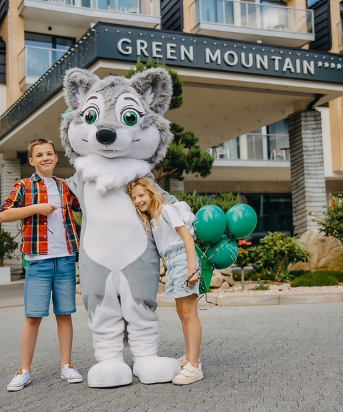Dzieci z maskotką Green Mountain przed wejściem do hotelu.