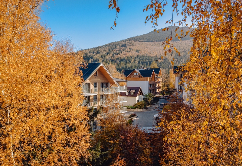 Autumn trees and Green Mountain Hotel***** & Apartments in Karpacz—mountain getaways with views.