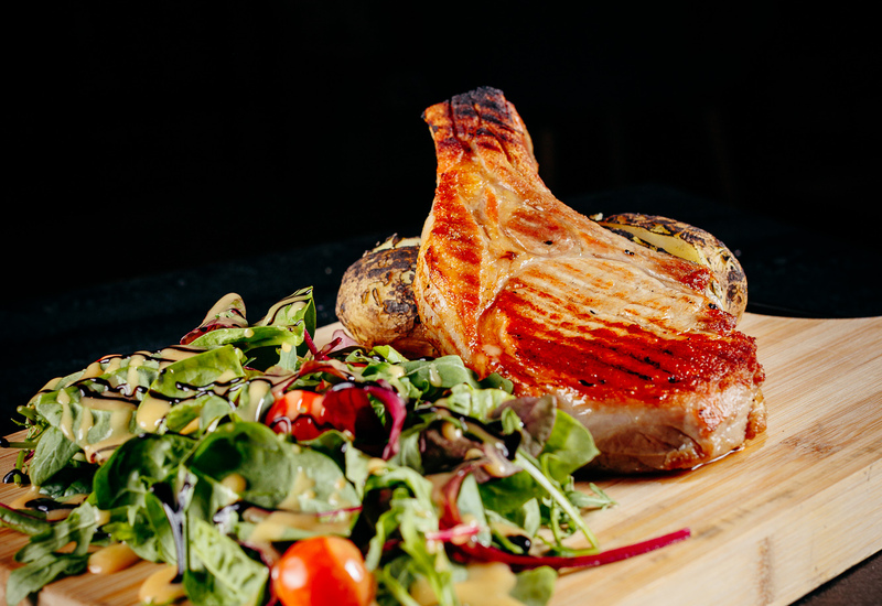 Meat dishes with a salad served on a wooden board at Green Mountain restaurant in Karpacz.