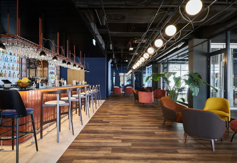 Stylowy bar i lounge w hotelu z miedzianym barem, wysokimi stołkami, wiszącymi kieliszkami, wygodnymi fotelami i ciepłym światłem