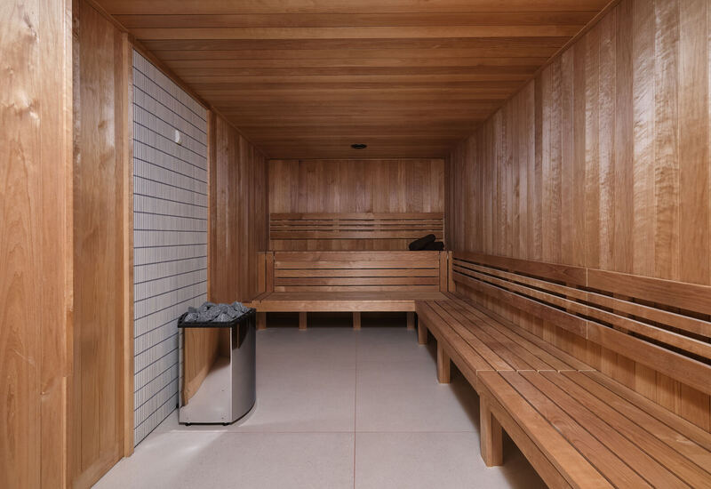 Wood-paneled spa sauna with tiered benches, stone heater and folded towels