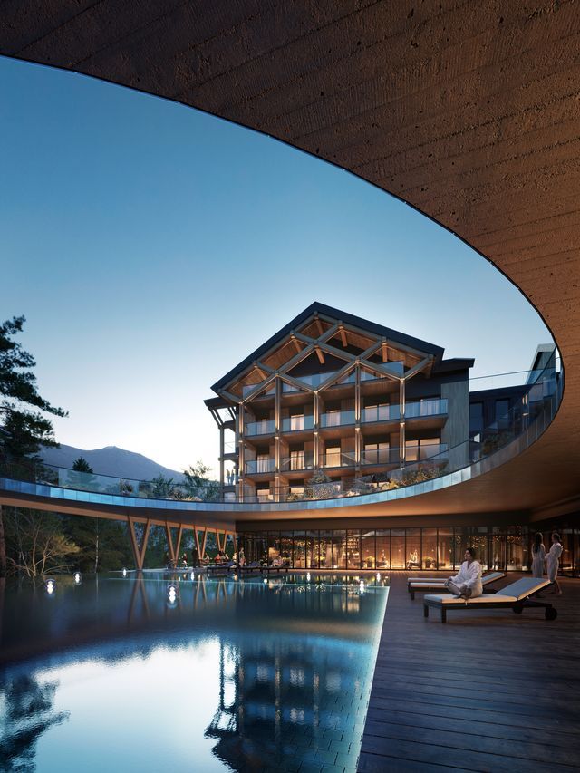 Nowoczesny górski hotel z drewnianą konstrukcją i balkonami, podświetlonym basenem, tarasem z leżakami i gośćmi w szlafrokach.