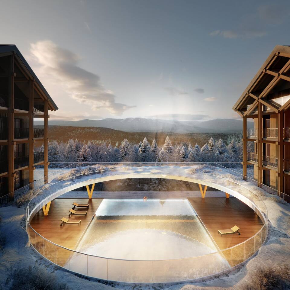 Ogrzewany okrągły basen z parą, drewniany taras i leżaki między górskimi willami, widok na zaśnieżony las