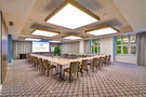 Nowoczesna sala konferencyjna w układzie U: drewniane stoły, tapicerowane krzesła, butelki wody, ekran z logo Old Town Haston, duże kwadratowe lampy