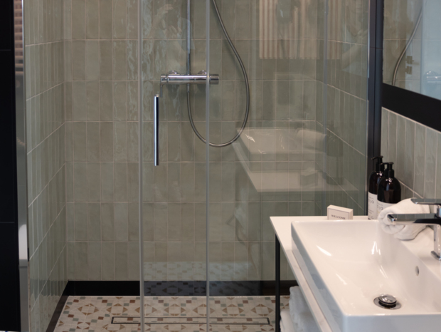 Nowoczesna łazienka hotelowa z prysznicem z szklaną kabiną, białą umywalką i miękkimi ręcznikami