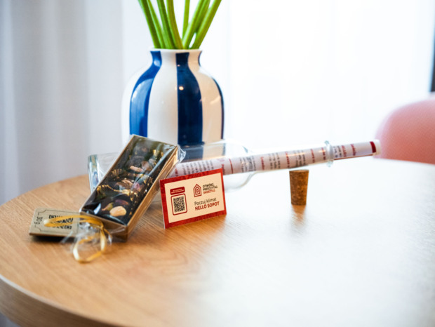 Drewniany stół z dekoracyjną niebiesko-białą wazonem, słodkim upominkiem i butelką z korkiem w hotelowym wnętrzu