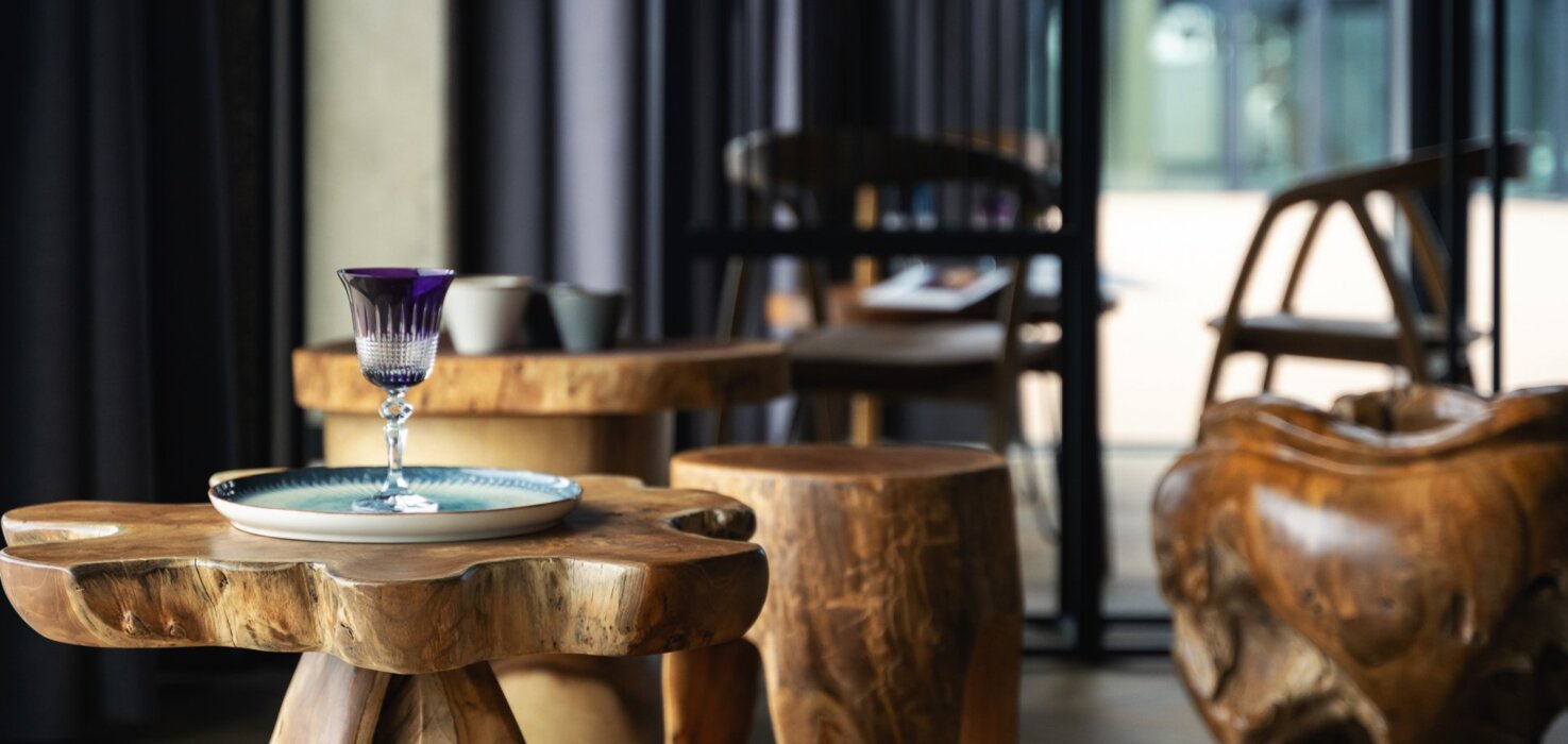 Cozy hotel lounge with unique wooden furniture and a decorative glass on a natural wood table.