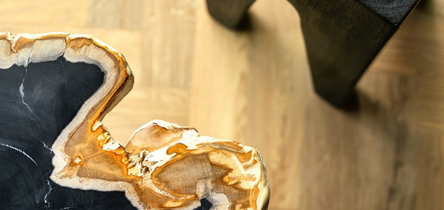 Close-up of luxury wooden table with natural edge and black base on light hardwood floor