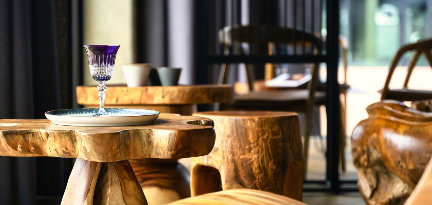 Stylowe wnętrze hotelowego lobby z rzeźbionymi drewnianymi meblami i dekoracyjnym fioletowym kieliszkiem na stole