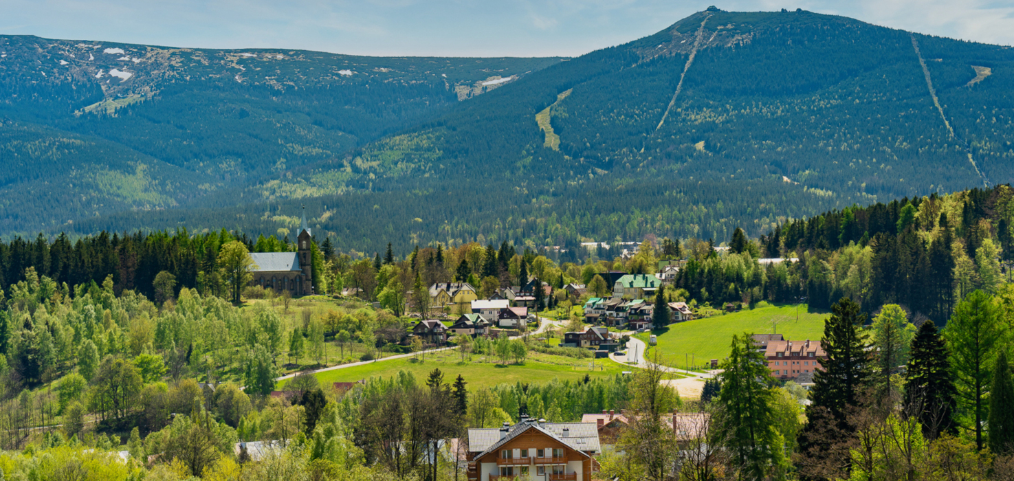 Malownicza wiejska osada w górach z domami i kościołem otoczona zielonymi lasami i pagórkami