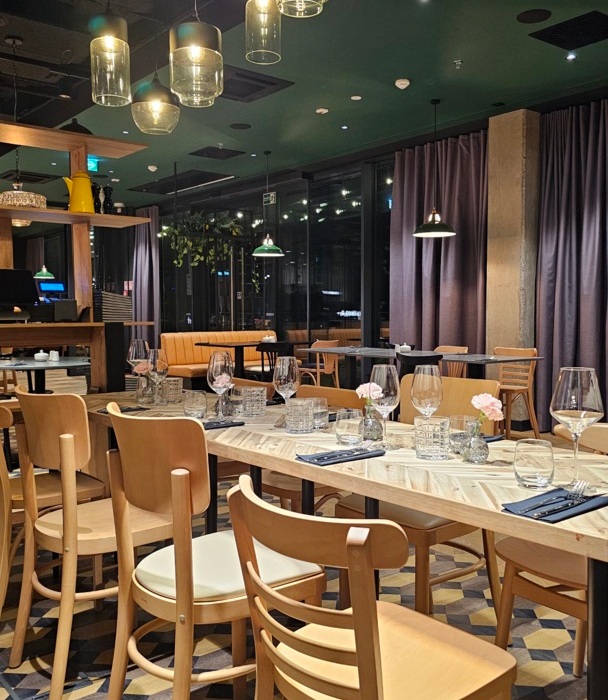 Nowoczesna restauracja z drewnianymi krzesłami, elegancko nakrytymi stołami i nastrojowym oświetleniem nad głową