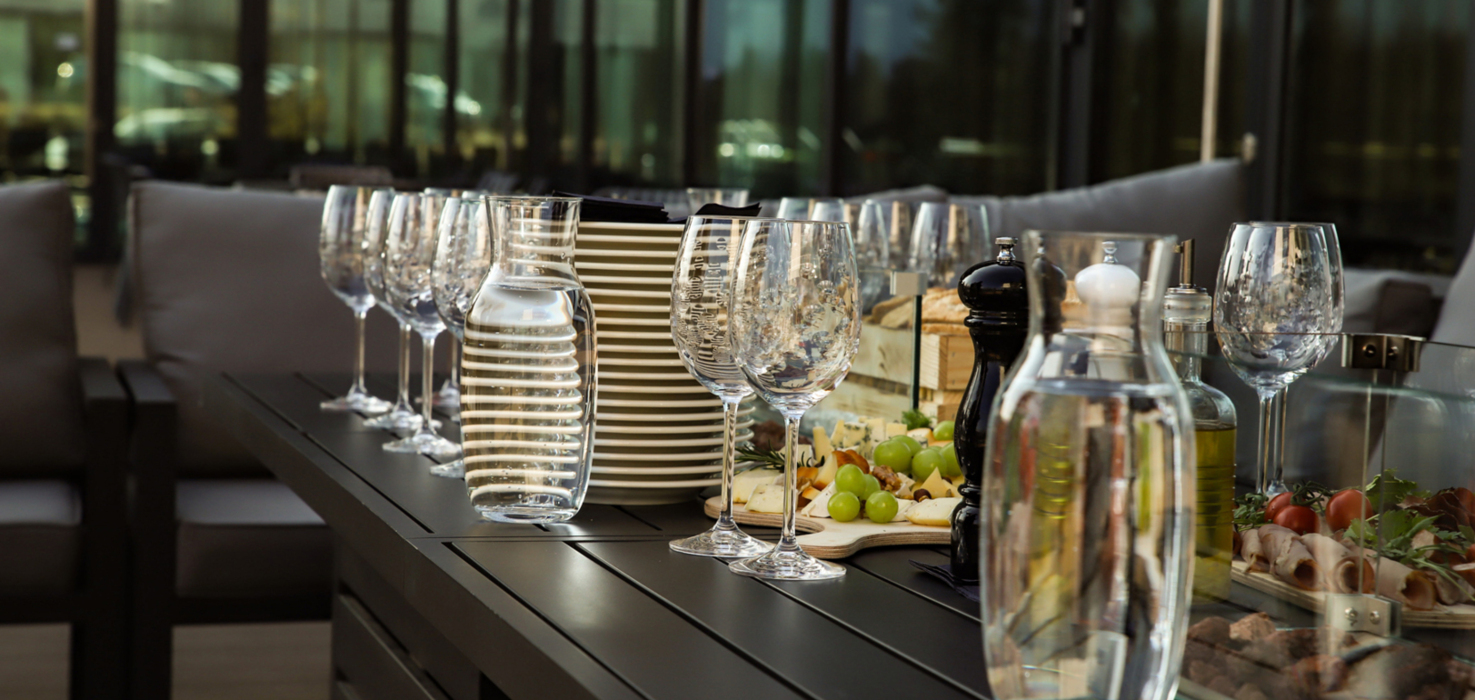 Elegancki stół z kieliszkami, karafkami wody, talerzami i deską serów z winogronami w przytulnym salonie hotelowym