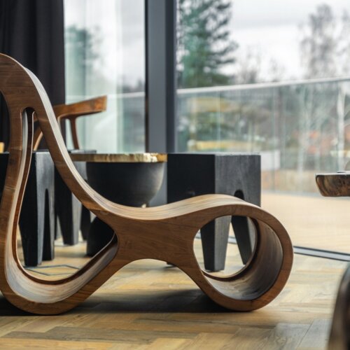 Moderne hölzerne Designer-Liege in einem Raum mit großen Fenstern und Blick auf die Hotelterrasse