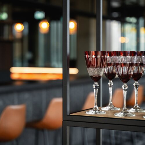 Elegante Kristallgläser mit rotem und violettem Glas in moderner Hotelbar präsentiert
