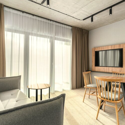 Moderner Hotellounge mit grauem Sofa, kleinem Holztisch, Esstisch mit vier Stühlen und hellen Gardinen