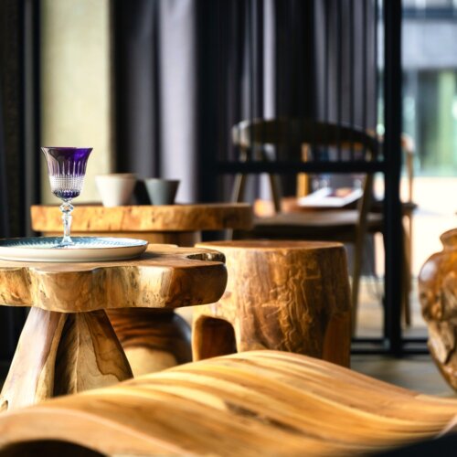 Stilvolles Hotellobby-Interieur mit geschnitzten Holzmöbeln und dekorativem lila Glas auf dem Tisch