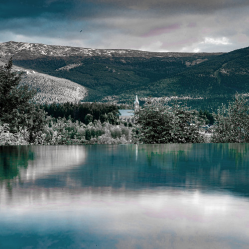 Infinity-Pool mit Blick auf Berglandschaft und eine Kirche umgeben von Bäumen