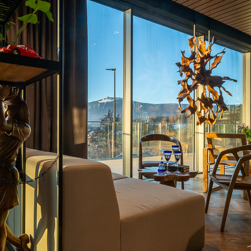 Moderner Hotellounge mit großen Fenstern mit Bergblick, Holzmöbeln und einem einzigartigen Holzleuchter