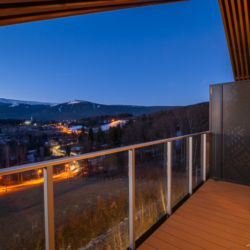 Hotelbalkon mit Panoramablick auf beleuchtetes Tal und schneebedeckte Berge bei Dämmerung