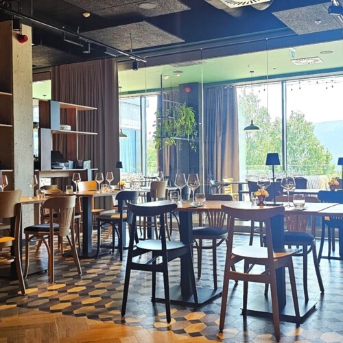 Großes Hotelrestaurant mit modernem Interieur, großen Fenstern und Blick auf bewaldete Hügel.
