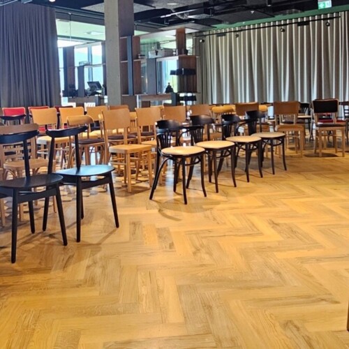 Konferenzraum mit Holzstühlen und großen Fenstern mit Blick auf Grünflächen und Berge