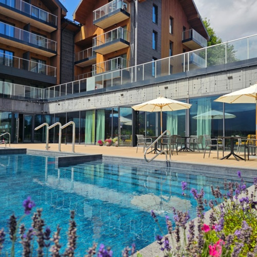 Hotelpool mit Terrasse zum Entspannen, Tischen unter Sonnenschirmen und modernem Gebäude mit Balkonen