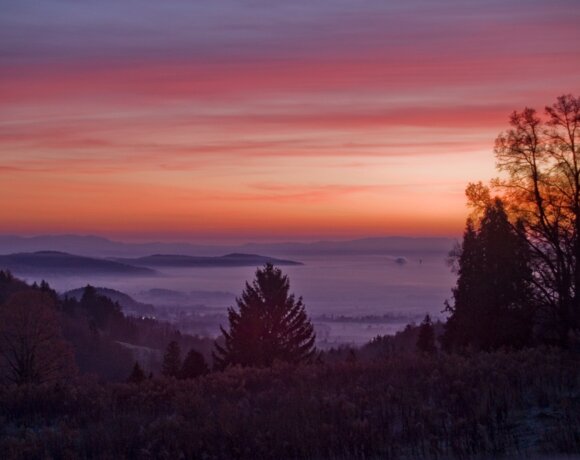 Tranquil mountain panorama at dusk with colorful sky and mist over forests and valleys