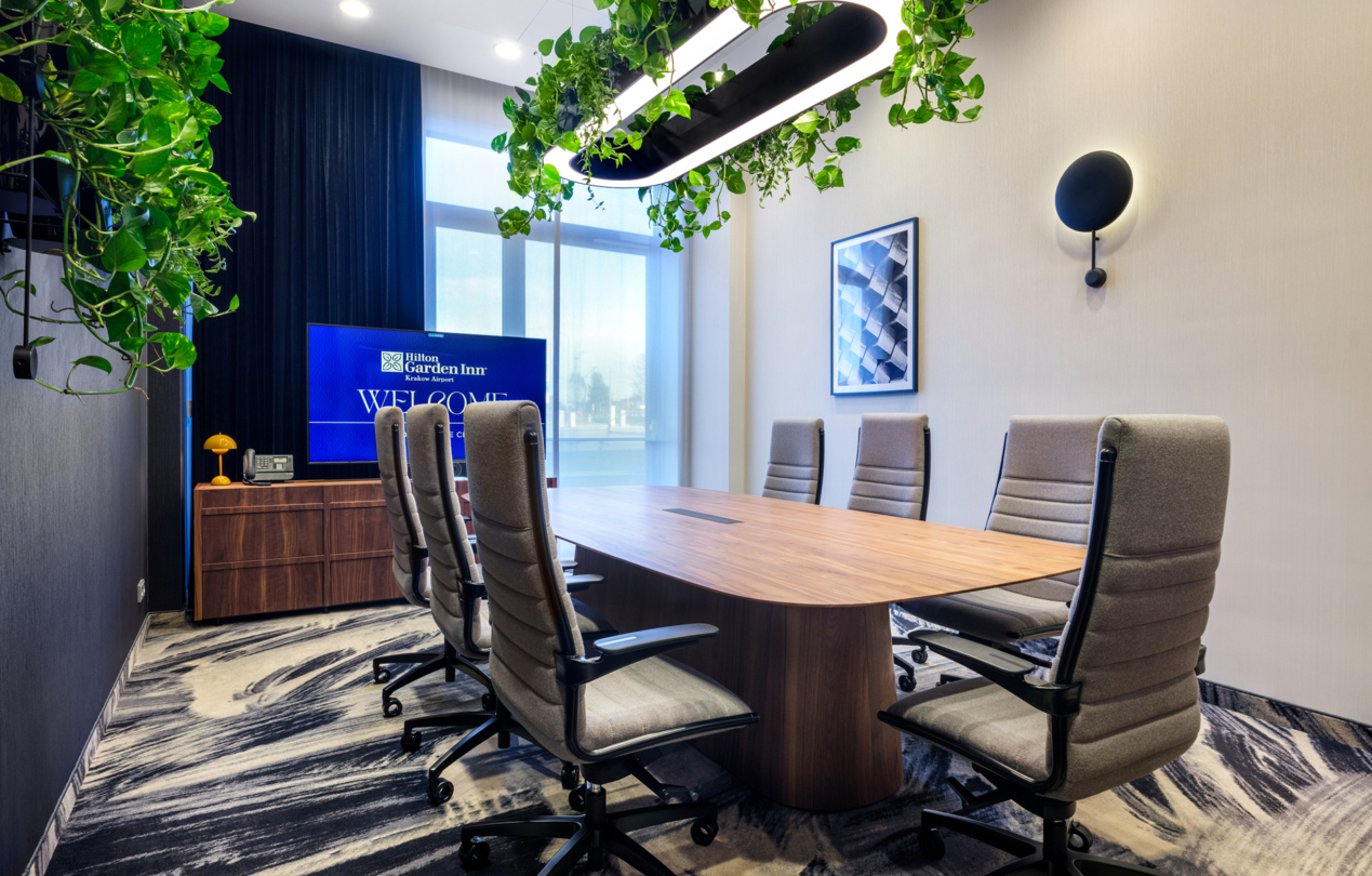 Wnętrze sali konferencyjnej ze stołem prezydialnym i obrotowymi fotelami