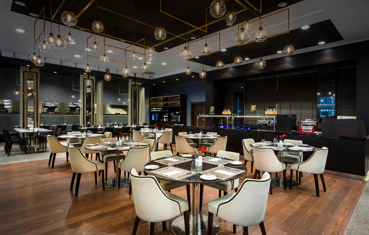 Wnętrze restauracji L'atmosphere z okrągłymi stolikami, na których znajduje się zastawa.