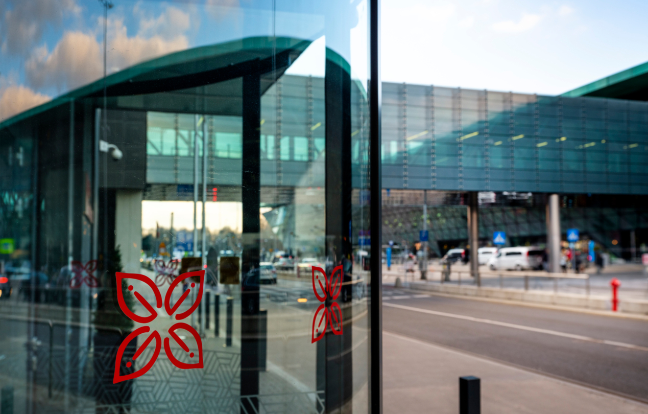 Przeszklone drzwi do hotelu z widokiem na pieszą kładkę łączącą hotel z terminalem lotniska