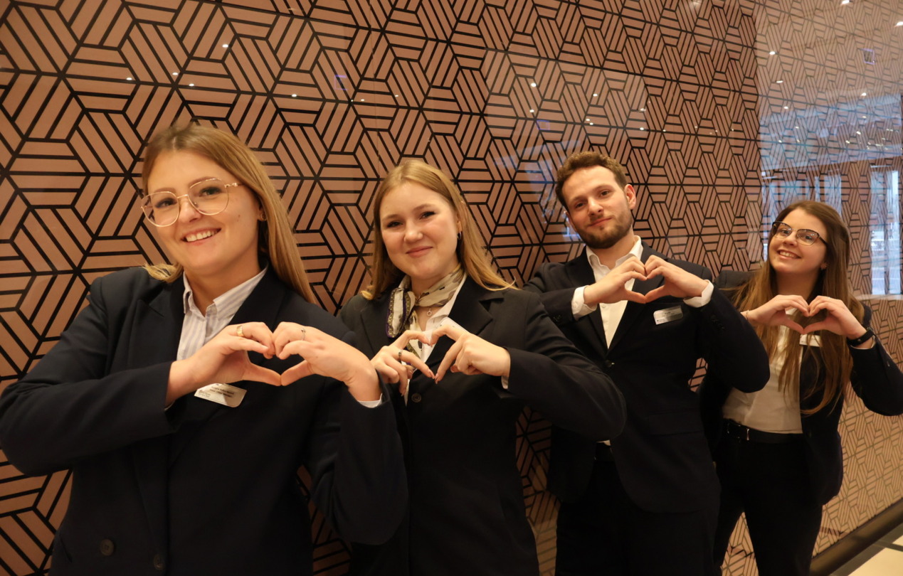 A group photo of hotel reception staff with their hands in the shape of a heart.