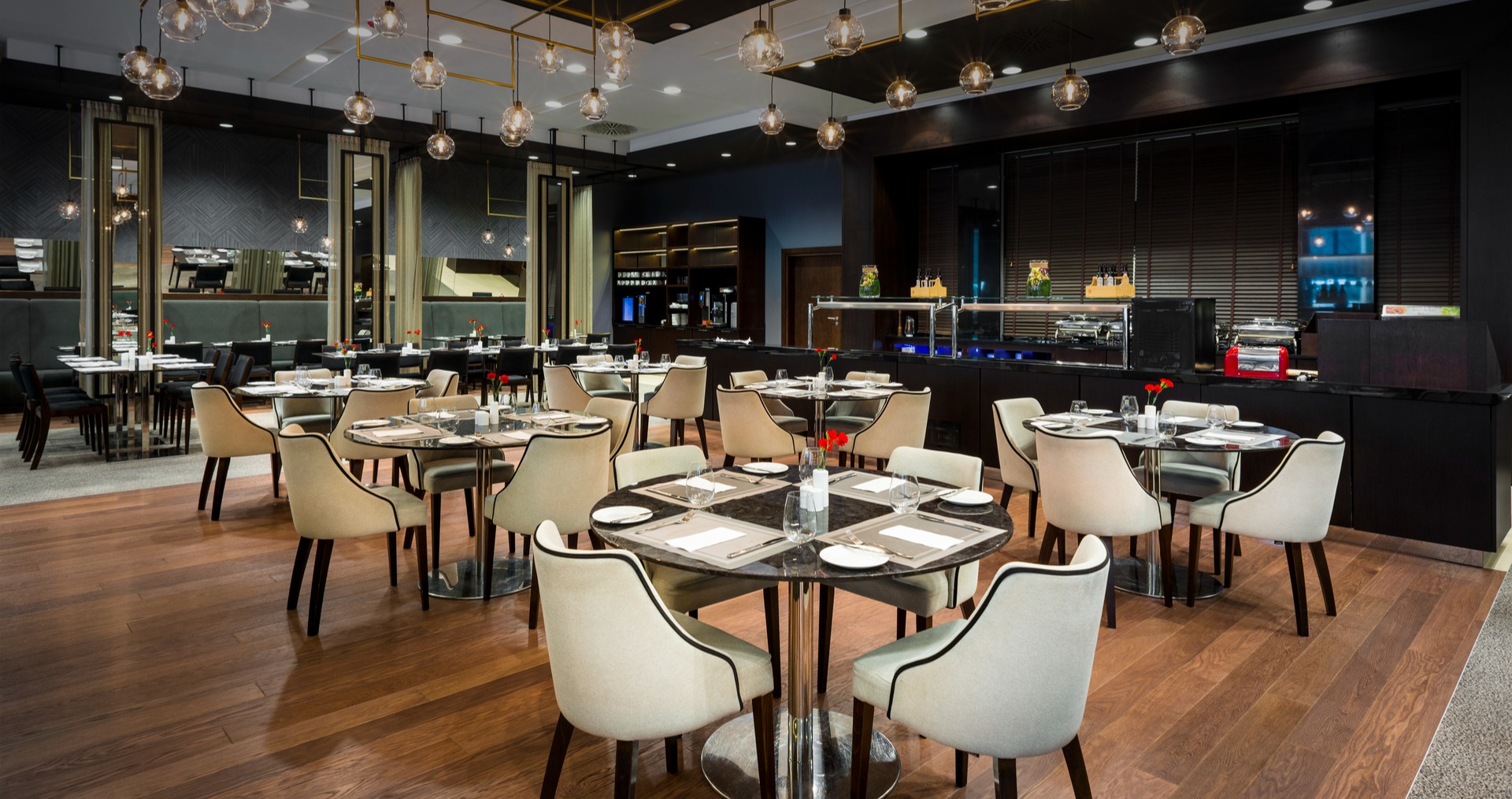 Wnętrze restauracji L'atmosphere z okrągłymi stolikami, na których znajduje się zastawa.