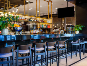 Zdjęcie hotelowego lobby baru wysokimi krzesłami, w tle butelki gatunkowych alkoholi