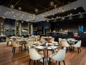 Wnętrze restauracji L'atmosphere z okrągłymi stolikami, na których znajduje się zastawa.