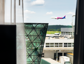 Widok z okna hotelowego pokoju na terminal lotniska i lądujący samolot