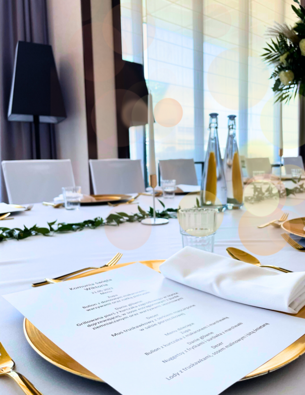 Uroczyście zastawiony stół z białym obrusem na którym leżą talerze z menu restauracji