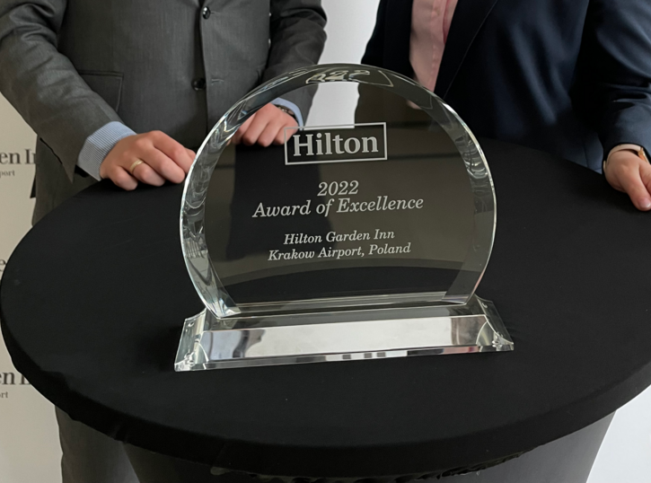 Szklana statuetka z wygrawerowanym napisem Hilton 2022 Award of Excelence.