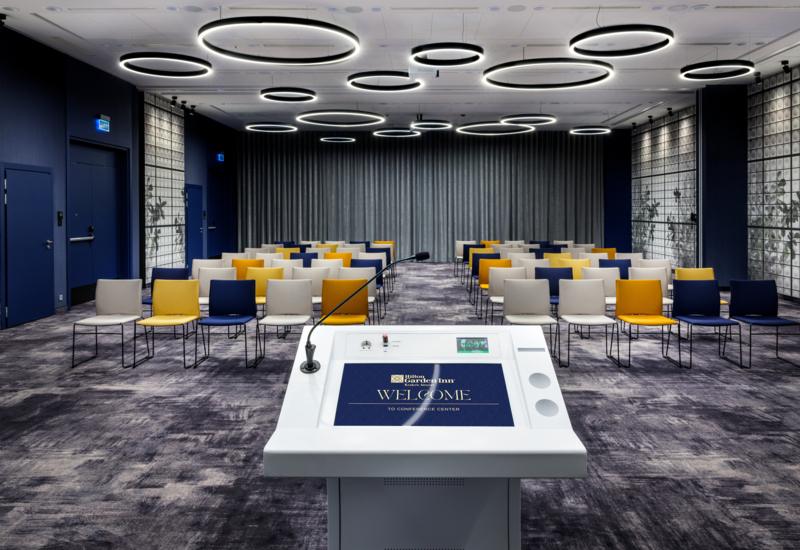 Zdjęcie sali konferencyjnej z perspektywy mównicy. W tle krzesła w ustawieniu teatralnym