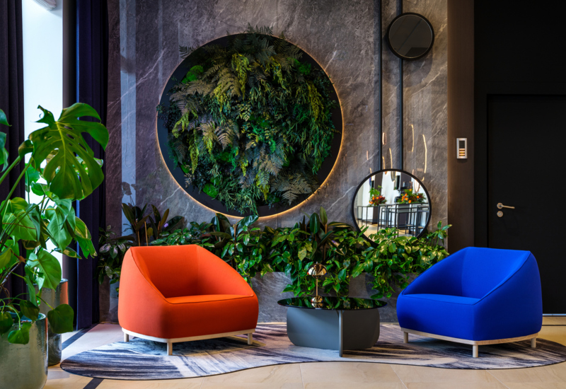 Dwa kolorowe fotele w hotelowym lobby na tle ściany z zielenią