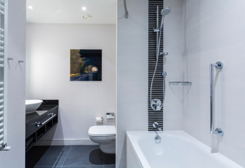 wnętrze hotelowej łazienki z wanną, w tle toaleta