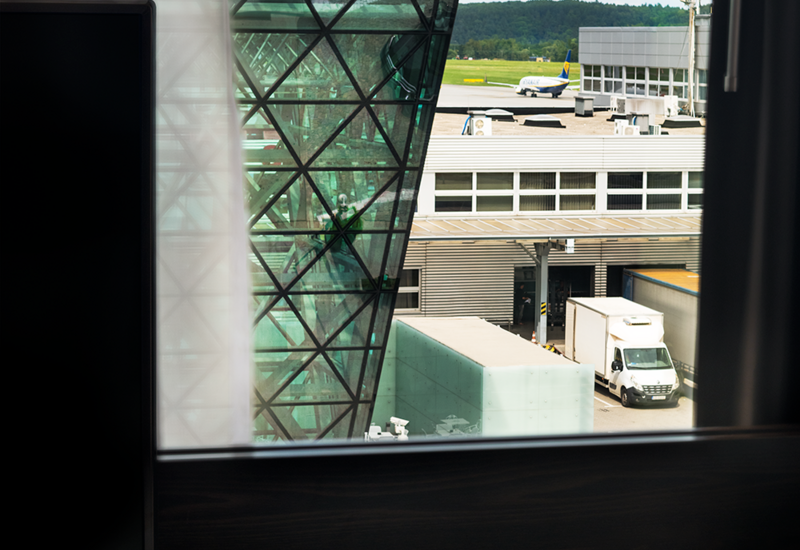 Widok z okna hotelowego pokoju na terminal lotniska i lądujący samolot