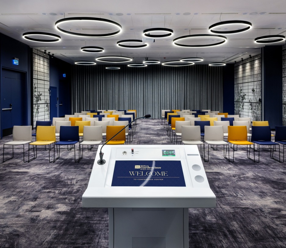 Zdjęcie sali konferencyjnej z perspektywy mównicy. W tle krzesła w ustawieniu teatralnym