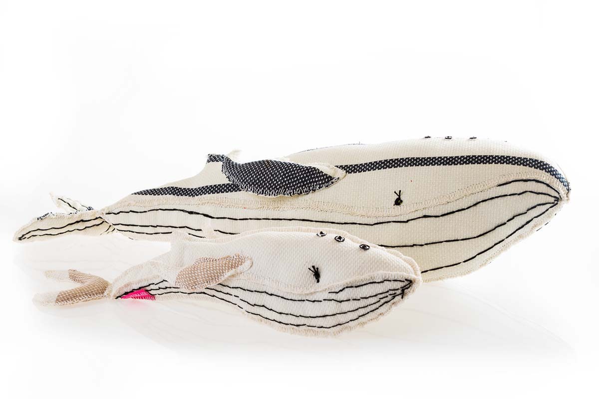 Two fabric whale toys in black, white, and beige with stitched details, showcasing playful and eco-friendly decor options